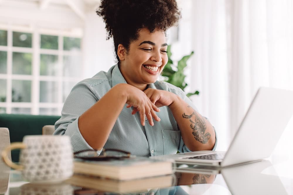 Positive woman video calling using laptop at home stock photo