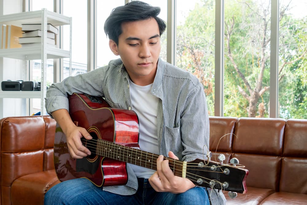 Curative member playing guitar during recovery unplugged session